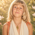 Young girl wearing a gold personalized Hamsa necklace in a sunlit garden
