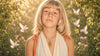 Young girl wearing a gold personalized Hamsa necklace in a sunlit garden