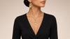 Woman wearing a gold personalized Hamsa necklace and matching Hamsa initial earring