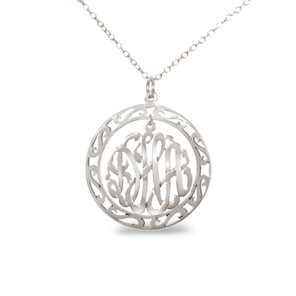 silver round monogram necklace hanging inside a hollow patterned circle pendant
